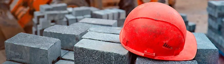 Casque de chantier rouge posé sur un tas de pavés.