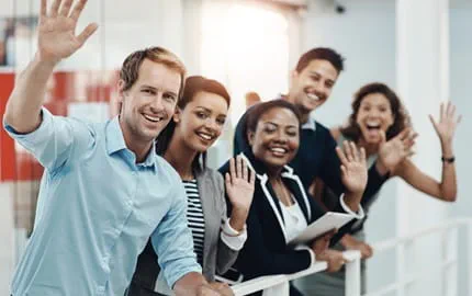 Une équipe de salariés font un signe de la main pour accueillir un nouvel employé.