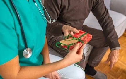 Un membre du personnel soignant recevant un cadeau pour noël.