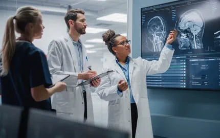3 médecins sont en réunion dans un laboratoire d’hôpital et décryptent sur un tableau les préconisations de l’IA. 