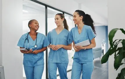 Trois soignantes souriantes ayant des horaires flexibles terminant leur journée de travail 