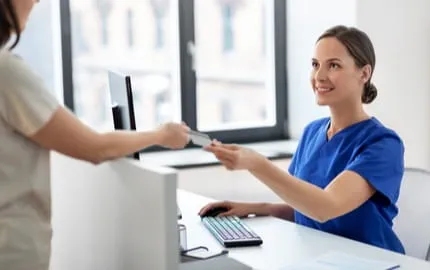 Une secrétaire médicale accueillant une patiente 