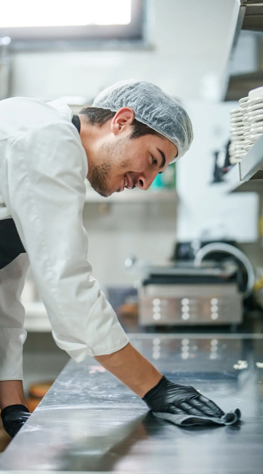 Ayudante del chef limpiando la encimera de la cocina