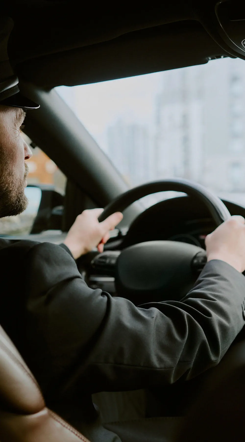 Hombre de mediana edad conduciendo coche en un entorno urbano durante el día