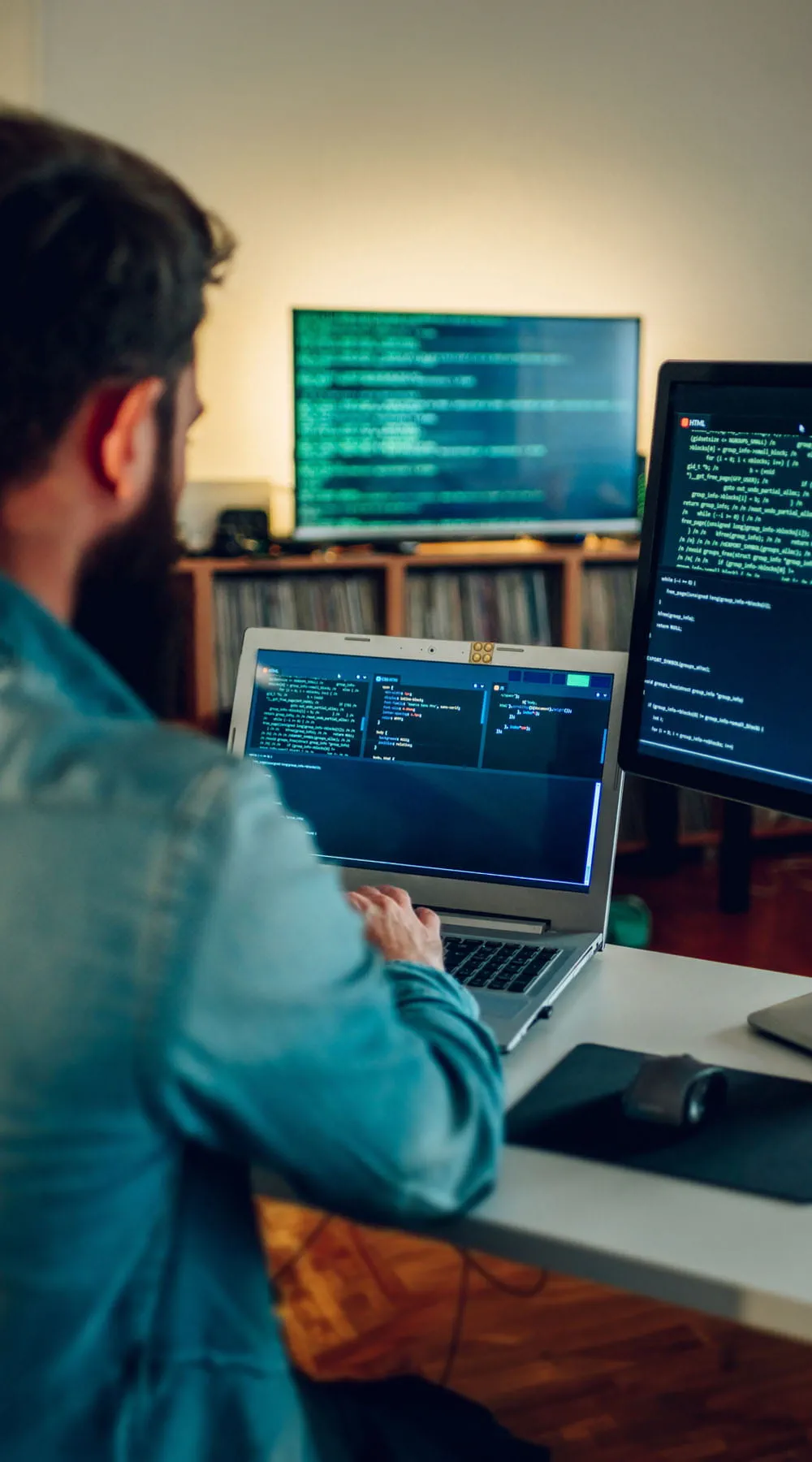 Vista trasera de un desarrollador de pila completa escribiendo código en su computadora portátil