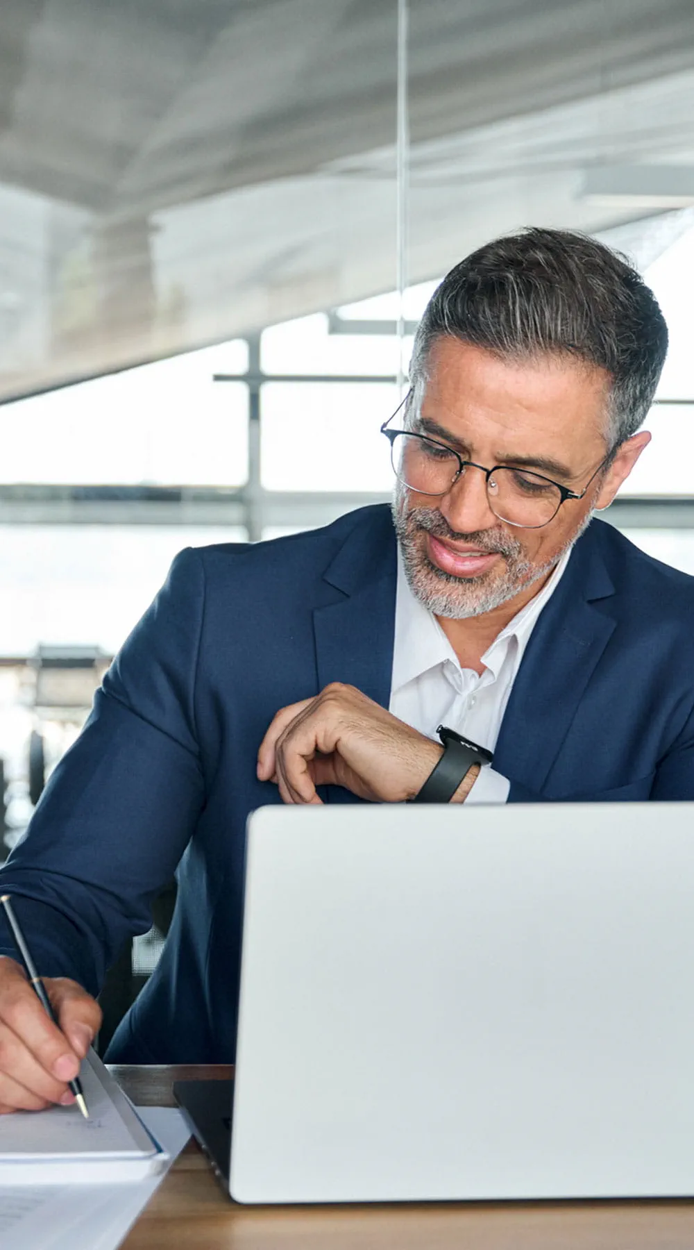 Hombre de negocios trabajando en una computadora portátil en la oficina escribiendo notas