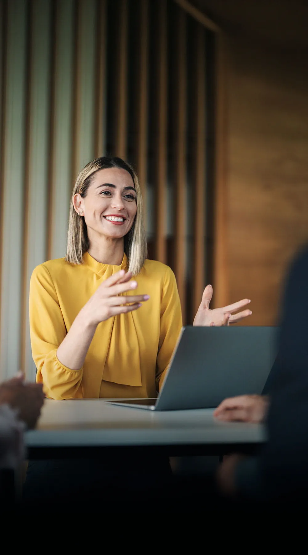 Directora vestida de amarillo en una reunión dentro de un despacho de oficina
