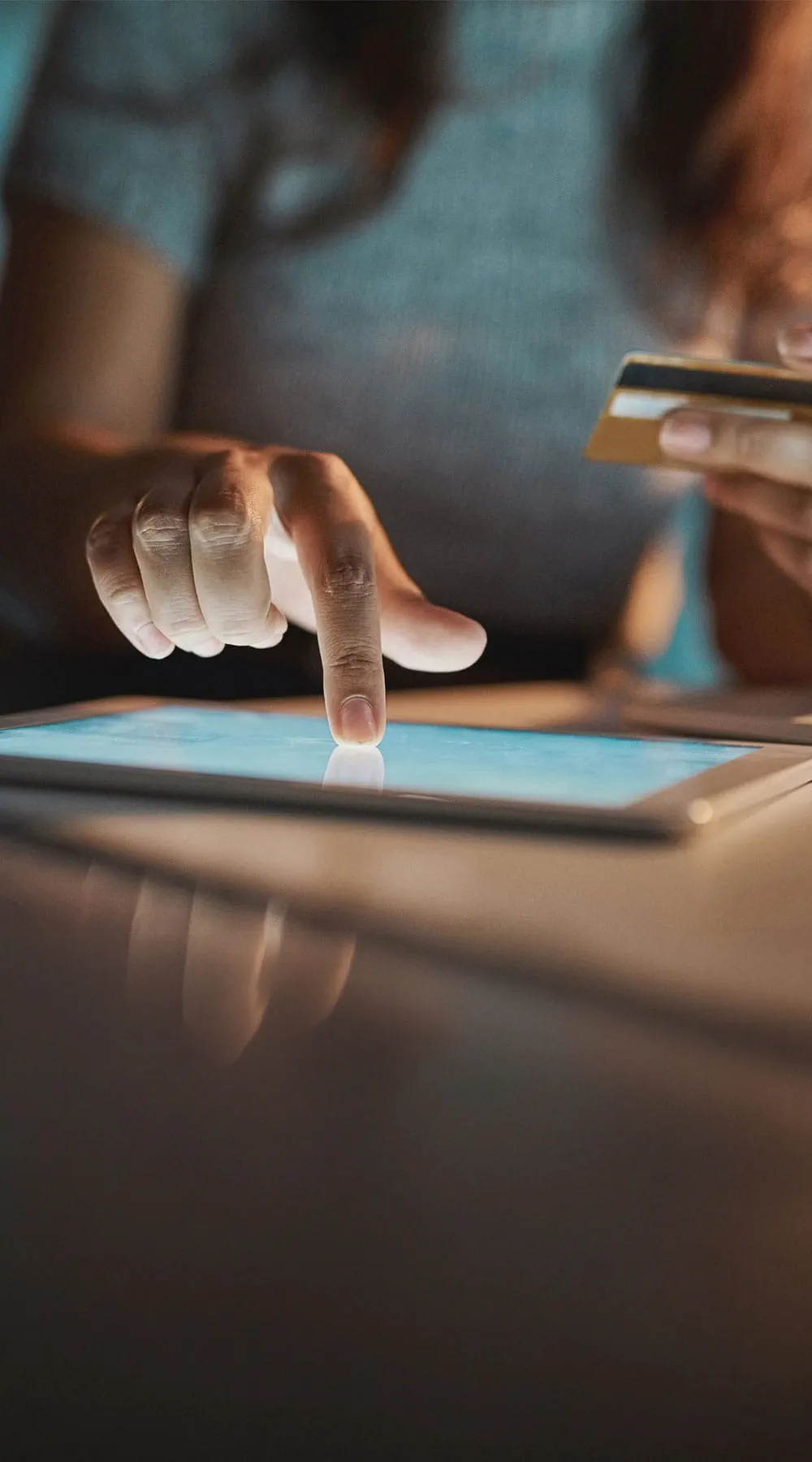 Mujer utilizando una tablet y una tarjeta para hacer compras por internet