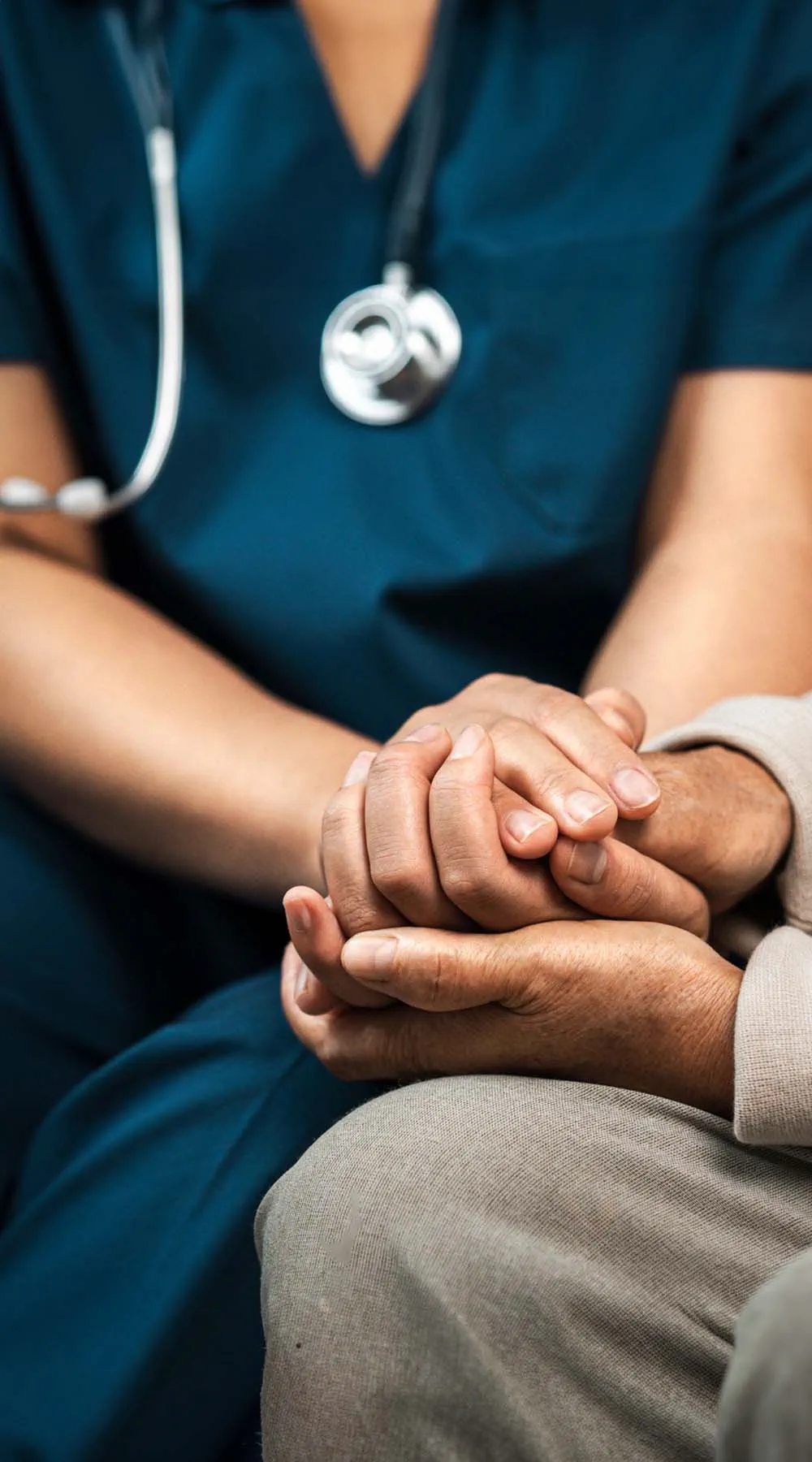 Enfermera cuidadora se toma de la mano para animar y consolar a una anciana