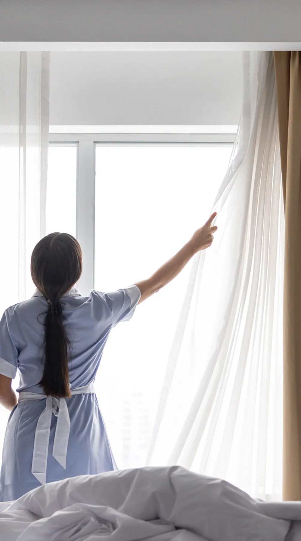 Personal de limpieza ajustando la ropa de cama en una habitación de hotel