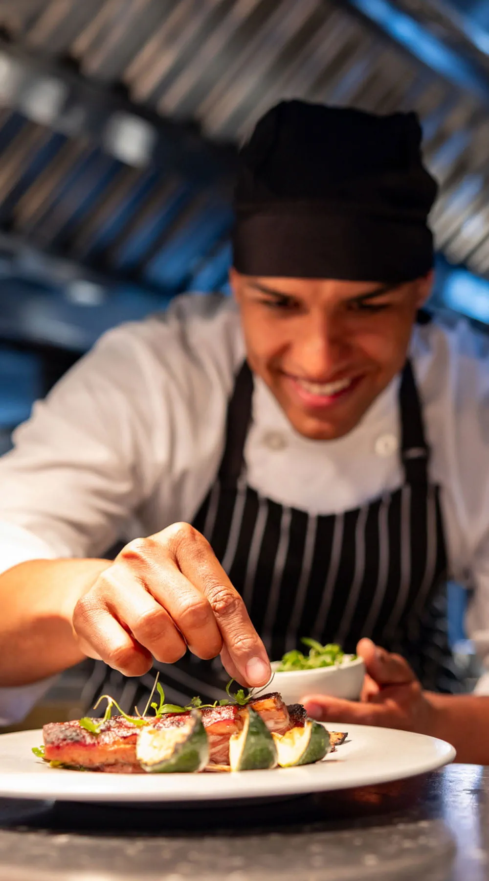 Chef decorando un plato mientras cocina en una cocina comercial