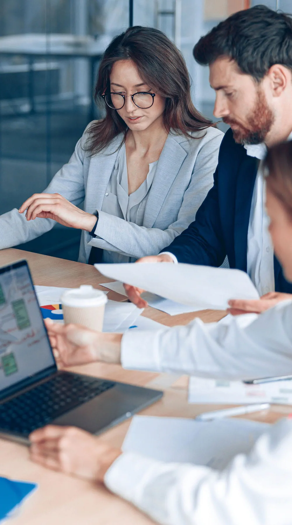 Equipo de negocios discutiendo documentos con gráficos y tablas en una oficina moderna