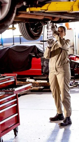 Técnico automotriz trabajando en un taller de autos con herramientas
