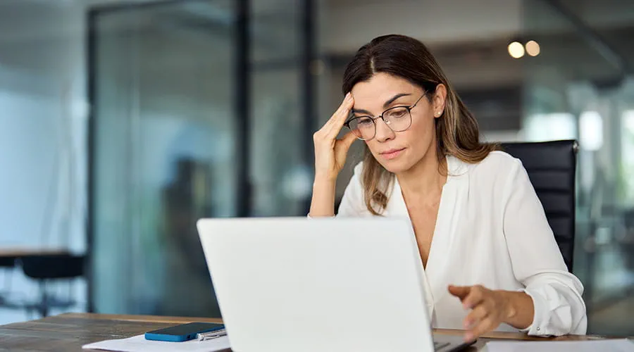 Mujer con gafas revisa seria información en un ordenador portátil