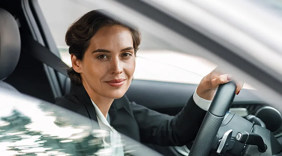 Mujer conduciendo un coche, parada mirando a cámara