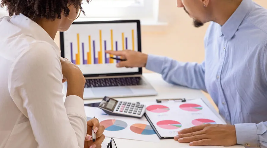 Dos personas revisando gráficos en una reunión