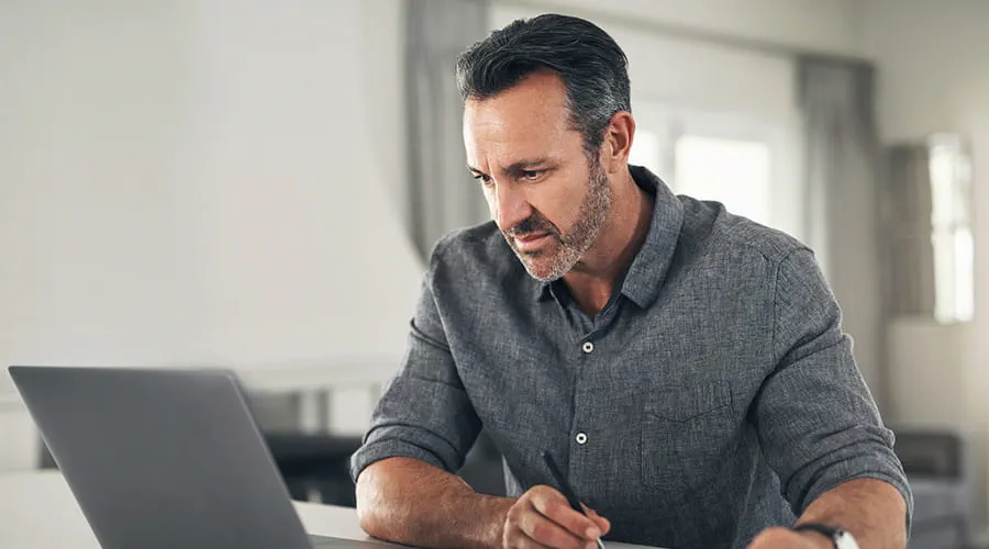 Hombre adulto revisando información en un ordenador portátil