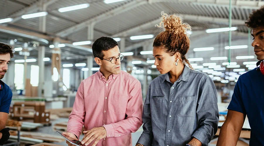 Arquitectos, ingenieros y personal de cuello azul trabajando juntos en una fábrica