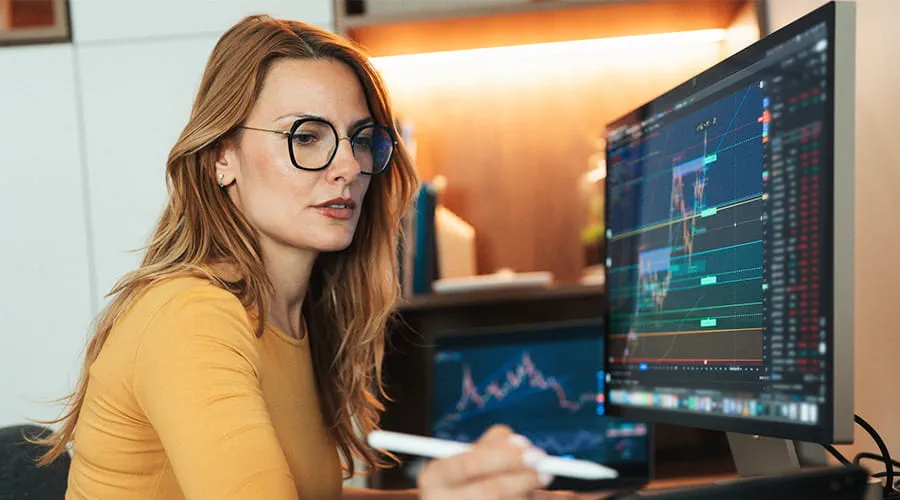 Mujer de negocios revisando gráficas en varios monitores