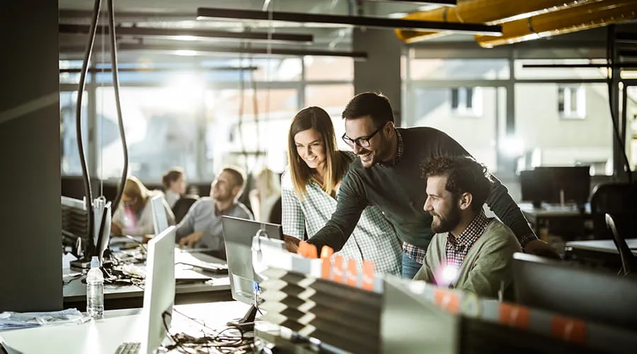 Grupo de tres programadores analizando datos en una pantalla