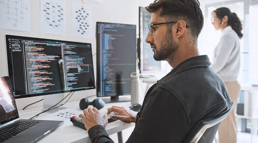 Hombre joven revisando datos en varios monitores