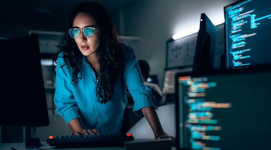 Programadora informática trabajando frente a varios monitores