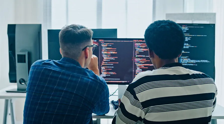 Dos desarrolladores de software trabajando frente a varias pantallas