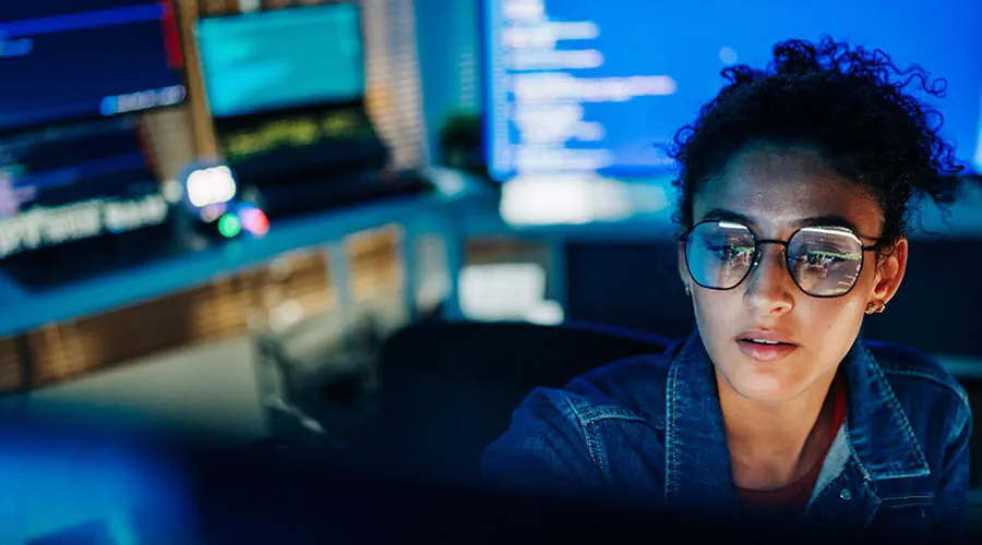 Programadora hispana centrada que trabaja con código en una oficina tecnológica
