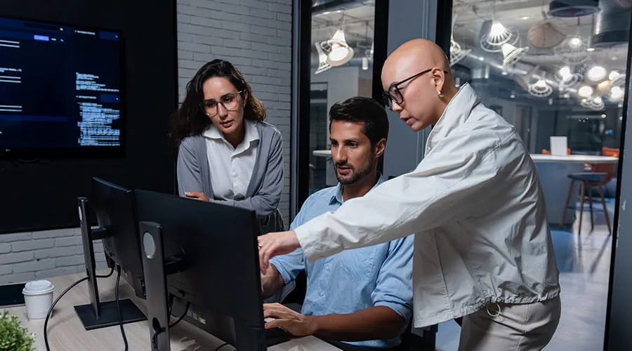 Equipo de desarrollo de software colaborando en ordenador durante la discusión de un proyecto de programación