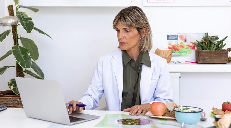 Doctora nutricionista en su consultorio trabajando en su ordenador portátil