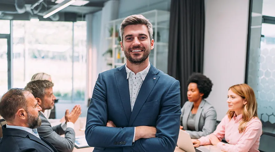 Hombre en primer plano con los brazos cruzados en una reunión de empresa Hombre en primer plano con los brazos cruzados en una reunión de empresa