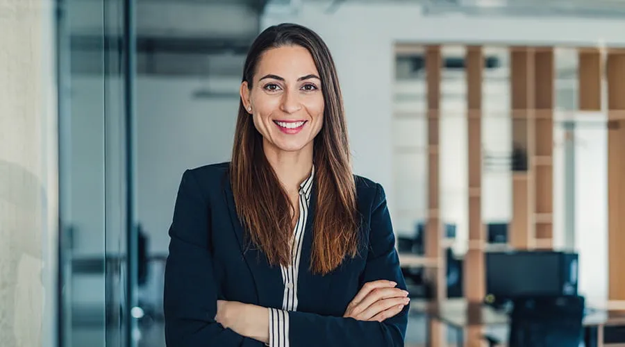 Mujer vestida con traje de chaqueta mirando a cámara en entorno de oficina Mujer vestida con traje de chaqueta mirando a cámara en entorno de oficina