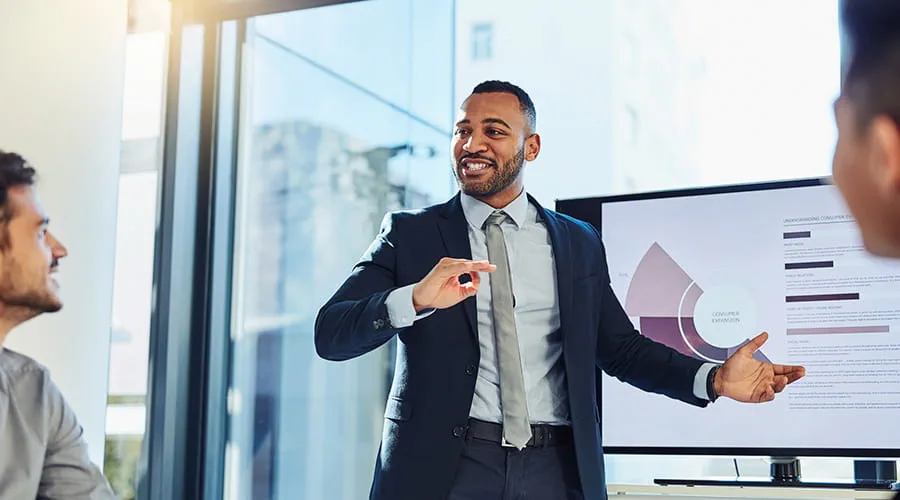 Hombre de negocios mostrando unos gráficos en una pantalla a dos personas