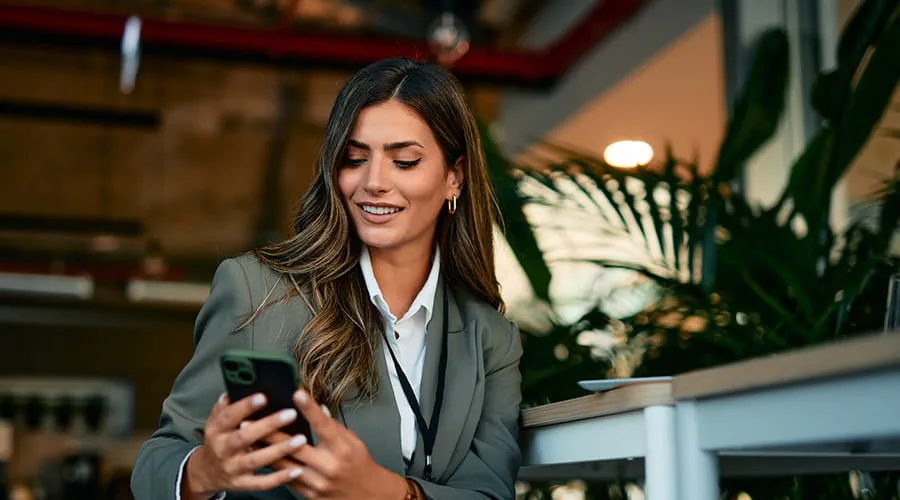Mujer de negocios usando teléfono inteligente en la cafetería de la oficina moderna