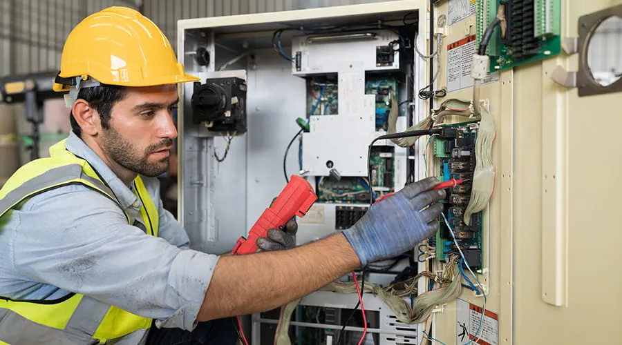 Trabajador electricista masculino reparando sistema eléctrico en fábrica