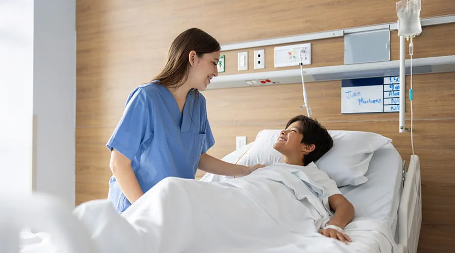 Niño hospitalizado sonriendo a la enfermera que lo cuida