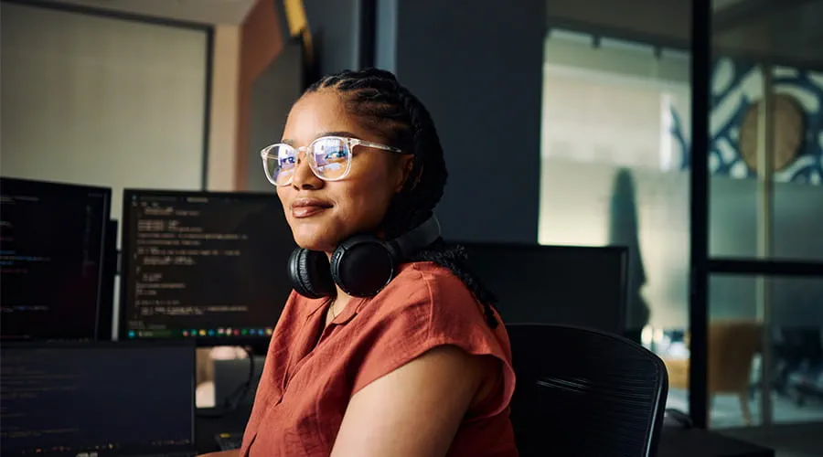 Joven programadora en su escritorio de trabajo mirando a cámara