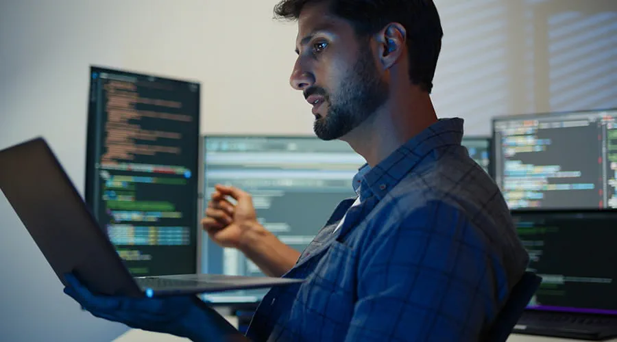 Técnico de software codificando en varios monitores al mismo tiempo
