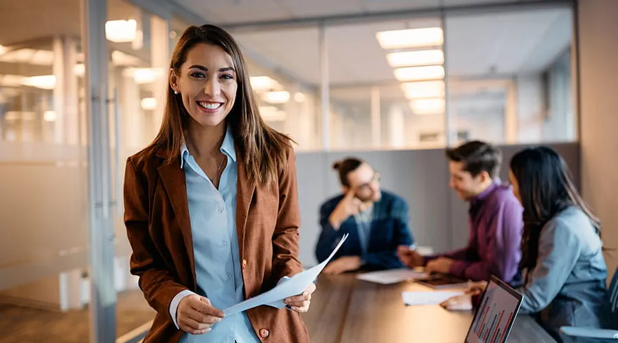 Mujer en una reunión en primer plano con el resto del equipo detrás hablando