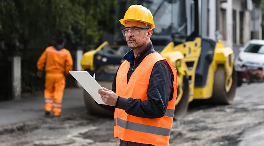 Supervisor de construcción revisando los planos mientras supervisa las obras viales