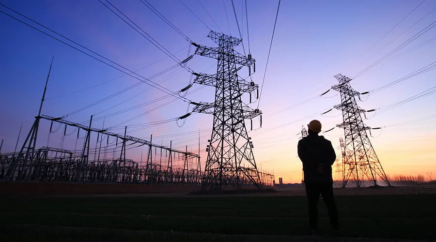Trabajadores de electricidad y silueta de pilón