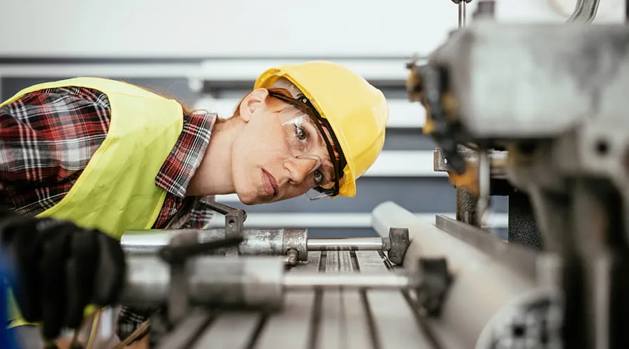 Mujer con equipo de protección trabajando en el taladro en la planta de la fábrica