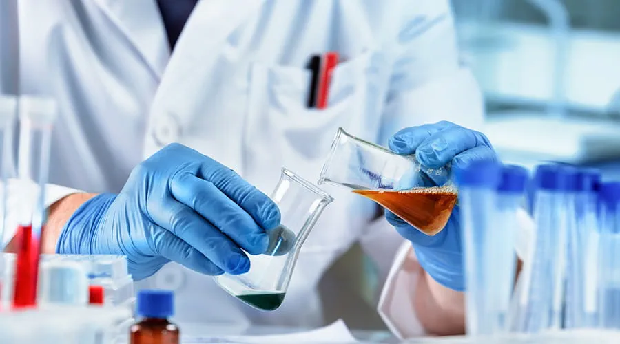Investigador que trabaja con fluidos en matraces en el laboratorio químico