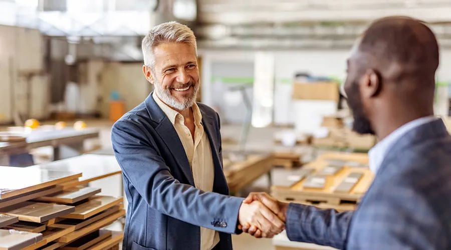 Empresarios se dan la mano en una fábrica para firmar un acuerdo de colaboración