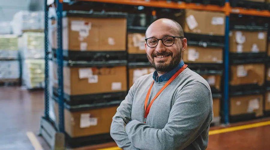 Retrato de un hombre de negocios sonriente de pie en el pasillo del almacén