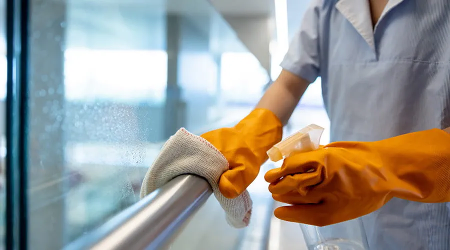Primer plano de un limpiador limpiando la barandilla de un hospital