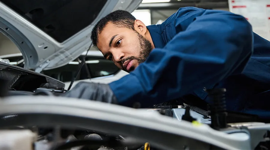 Mecánico inspeccionando el motor de un vehículo en el taller