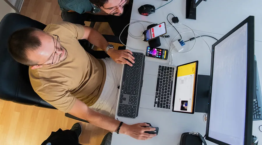 Vista superior de un programador probando las aplicaciones de los teléfonos inteligentes