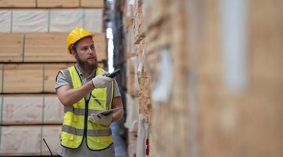 Trabajador verifica los artículos de paletas de madera utilizando un dispositivo portátil