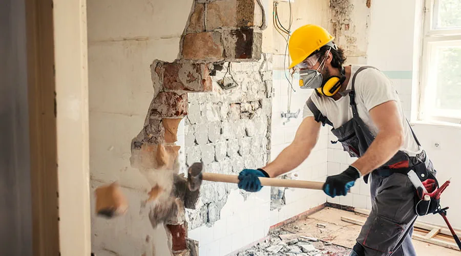 Trabajador usando martillo para derribar un muro